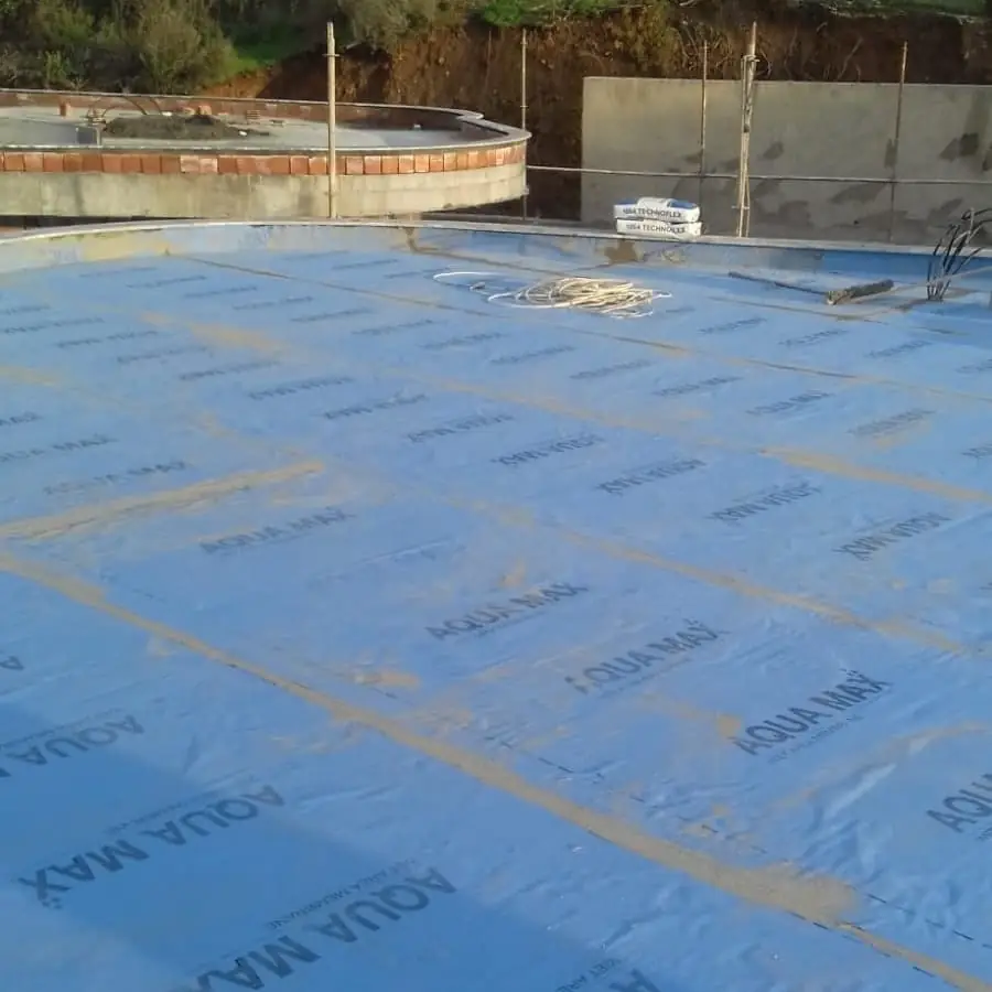 Betonarme döşemeyi kaplayan mavi su yalıtım örtüsü, arkada tuğla bordürlü yuvarlak havuz kabası