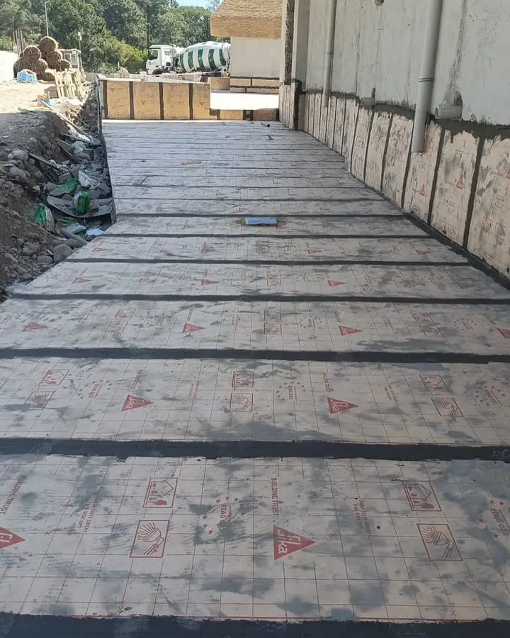 Bina duvarı boyunca serilen koruma levhaları ve ek yerlerini kapatan siyah bitümlü bant şeritleri