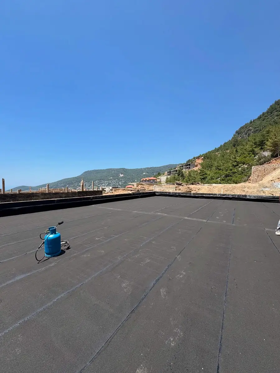 Dağ manzaralı şantiyede bitümlü membranla tümüyle kaplanmış geniş beton döşeme ve şalome tüpü