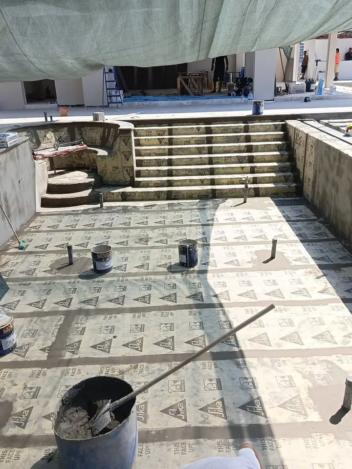Havuz tabanı ve merdivenlerindeki yalıtım levhaları, önde harç kovası ve mala ile ek dolgu hazırlığı