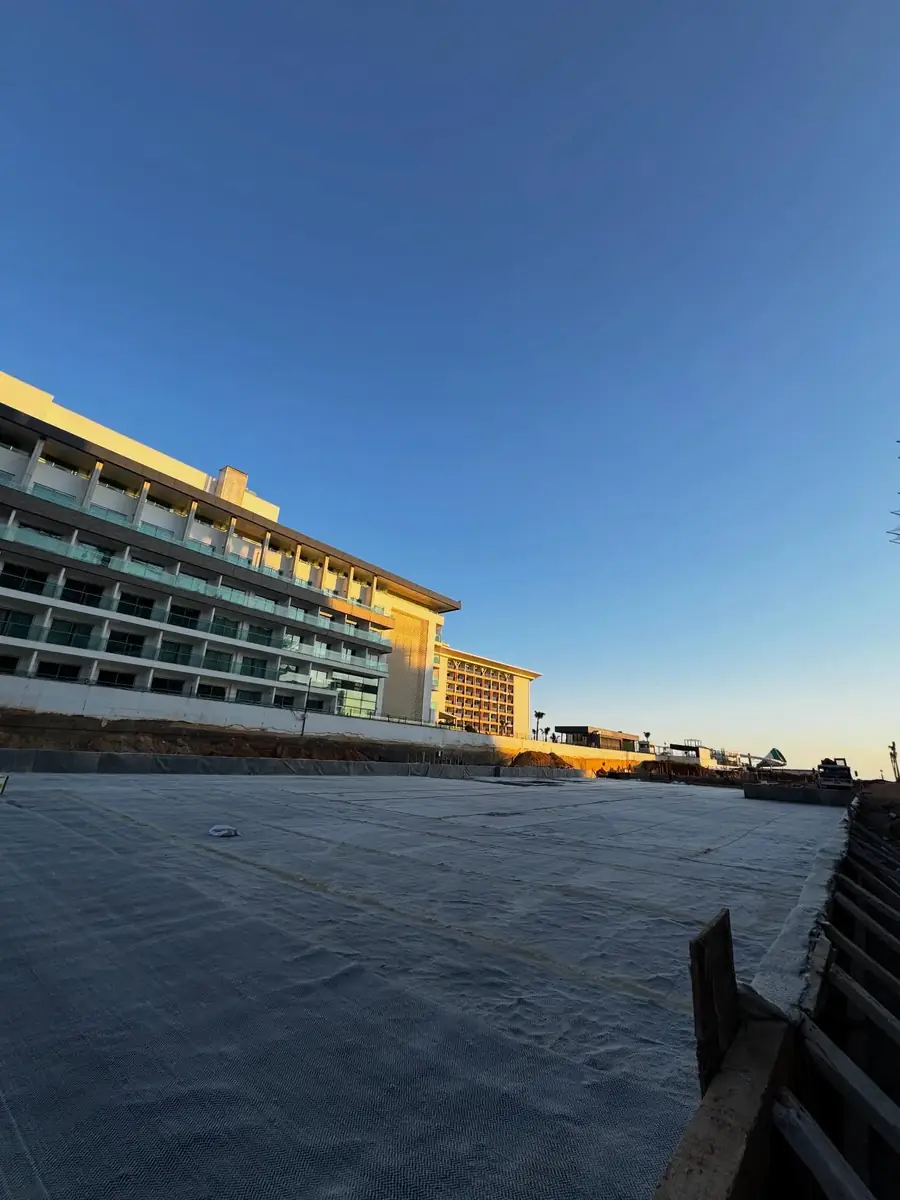 Otel inşaatında geniş beton platform üzerine serilen gri koruma örtüsü, gün doğumu genel görünümü